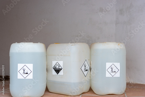 Bottles or jerricans with corrosive and harmful liquids for the environment, danger labels according to the international agreement on dangerous goods (ADR). photo