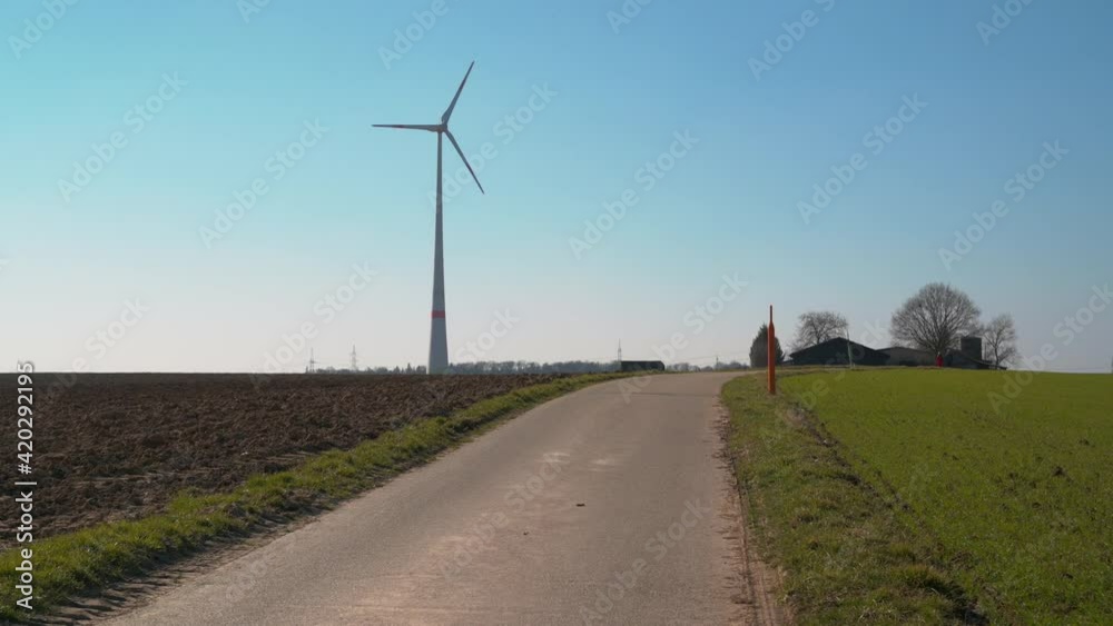 A closeup shot of a road leading to the windmill on the land A closeup shot of a road leading to the windmill on the land