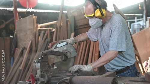 Elderly Asian carpenter working in the carpenter workshop.