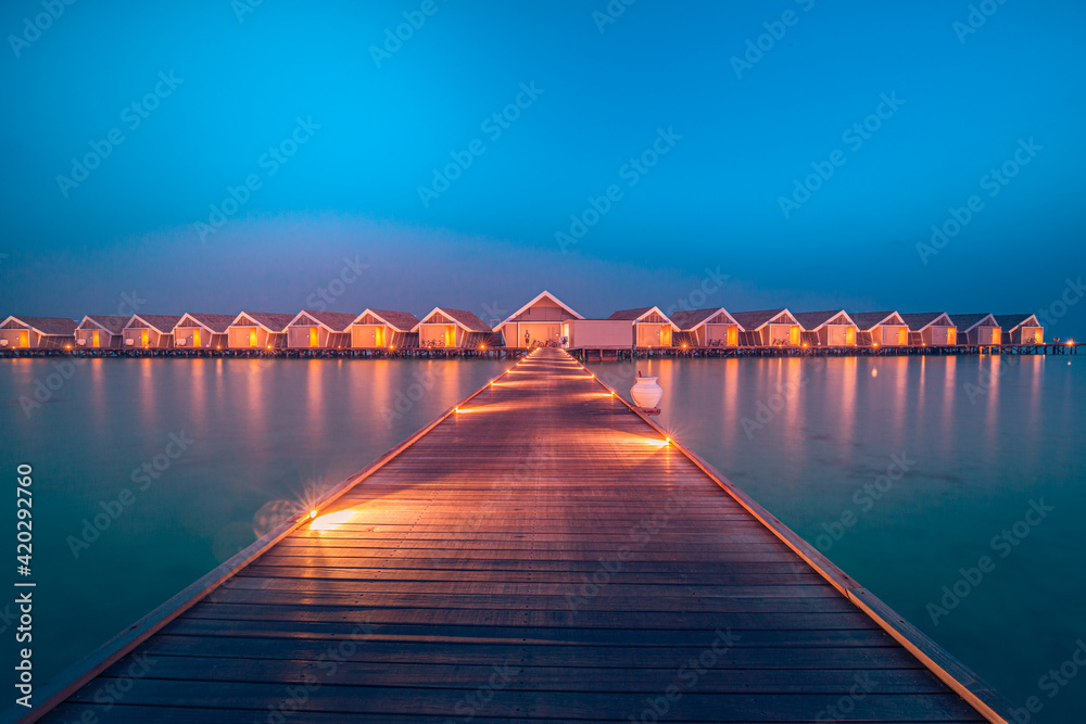 Amazing sunset panorama at Maldives. Luxury resort hotel villas seascape with soft led lights under colorful sky. Ocean lagoon, stunning romantic skyscape, seascape. Relax inspirational vacation beach