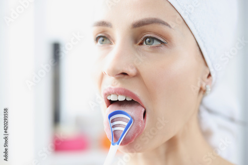 Woman cleans her tongue with special scraper