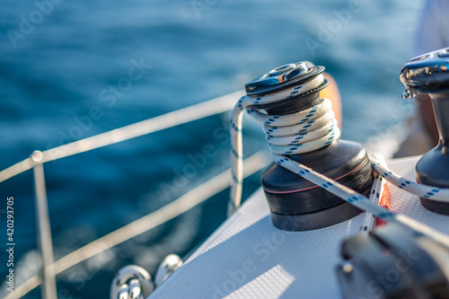 Closeup details of sailing winch equipment on a boat when sailing on the water in a sunny day. Sailboat sailing template in blue ocean sea photo