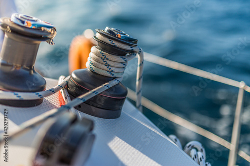 Closeup details of sailing winch equipment on a boat when sailing on the water in a sunny day. Sailboat sailing template in blue ocean sea © icemanphotos