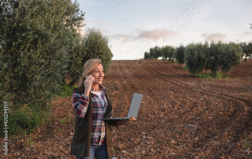 Female field engineer using computer in agricultural plantation. Integration of women in the field, agriculture and happy women concepts