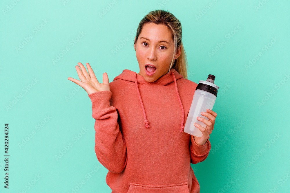 Young caucasian sport woman drinking water isolated on blue backgroundsurprised and shocked. Young caucasian sport woman drinking water isolated on blue backgroundsurprised and shocked.