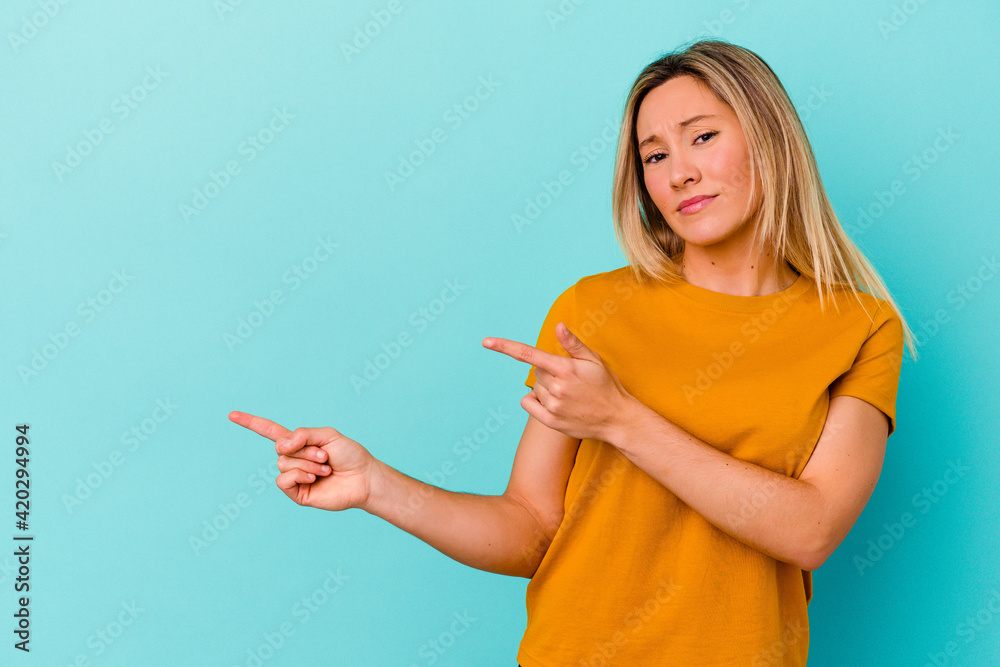 Young mixed race woman isolated on blue background shocked pointing with index fingers to a copy space. Young mixed race woman isolated on blue background shocked pointing with index fingers to a copy space.