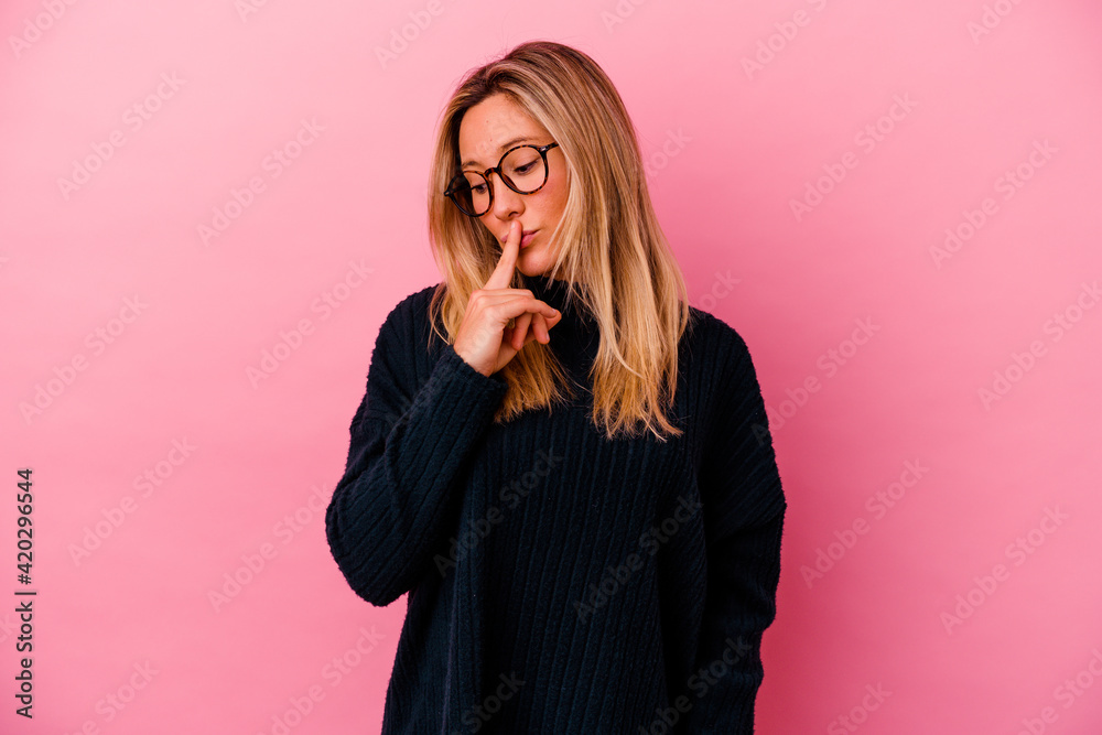 Young mixed race woman isolated on pink background keeping a secret or asking for silence. Young mixed race woman isolated on pink background keeping a secret or asking for silence.