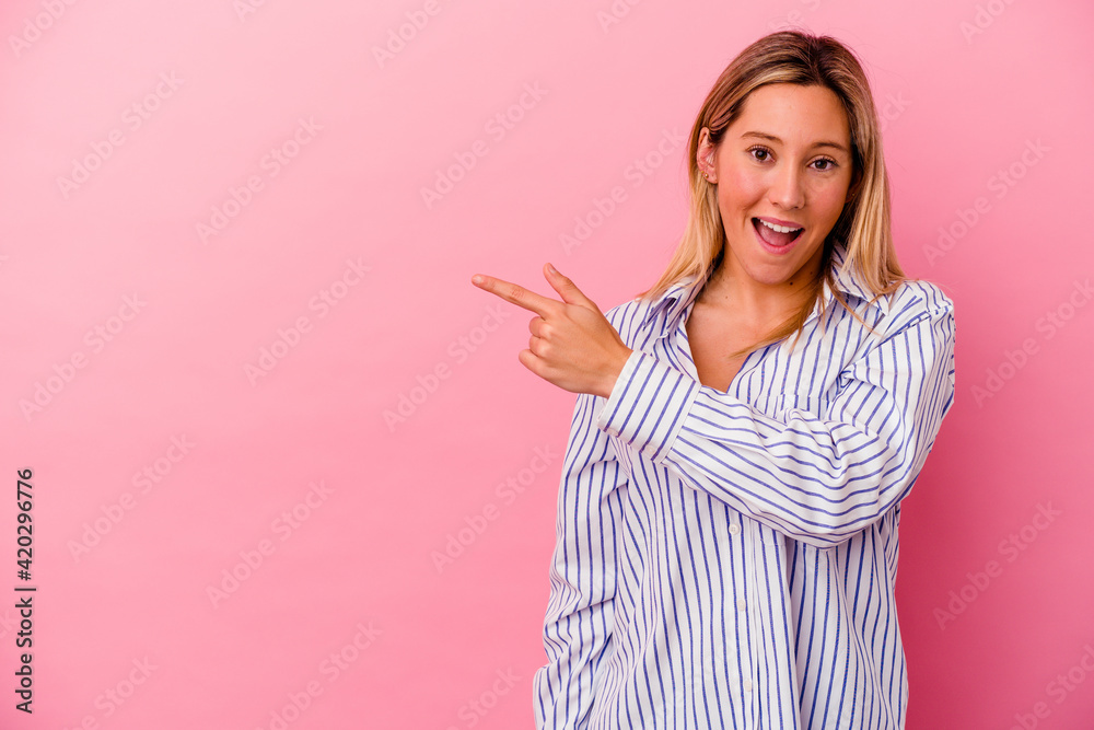 Young mixed race woman isolated on pink background smiling and pointing aside, showing something at blank space. Young mixed race woman isolated on pink background smiling and pointing aside, showing something at blank space.