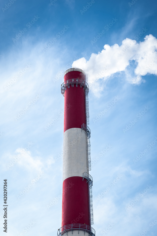 Industrial pipe against blue sky. Smoke from chimney. Air pollution. Waste burning for energy. Incineration factory. Alternative energy form trash. Vertical, close up, copy space
