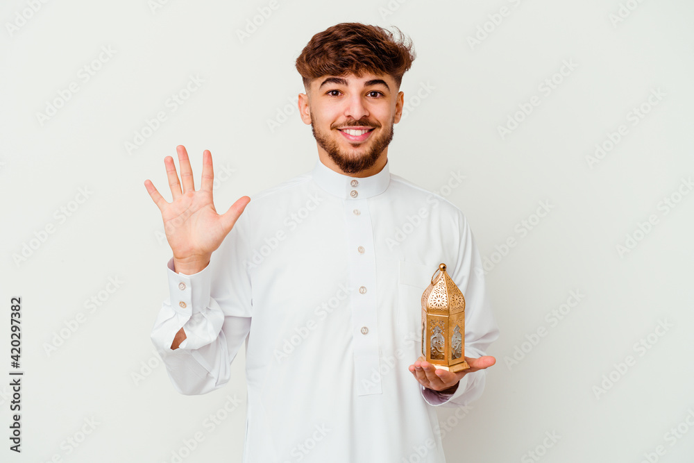 custom made wallpaper toronto digitalYoung Moroccan man wearing a typical arab clothes holding a ramadan lamp isolated on white background smiling cheerful showing number five with fingers.