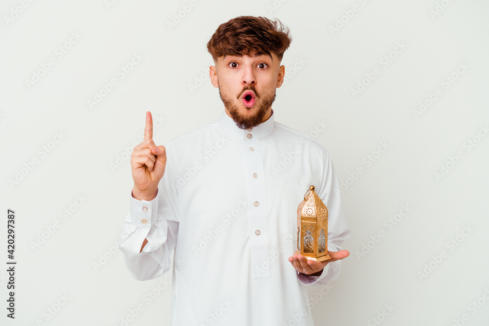 Young Moroccan man wearing a typical arab clothes holding a ramadan lamp isolated on white background having some great idea, concept of creativity. Young Moroccan man wearing a typical arab clothes holding a ramadan lamp isolated on white background having some great idea, concept of creativity.