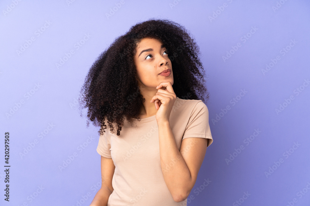 Young african american woman isolated on purple background and looking up