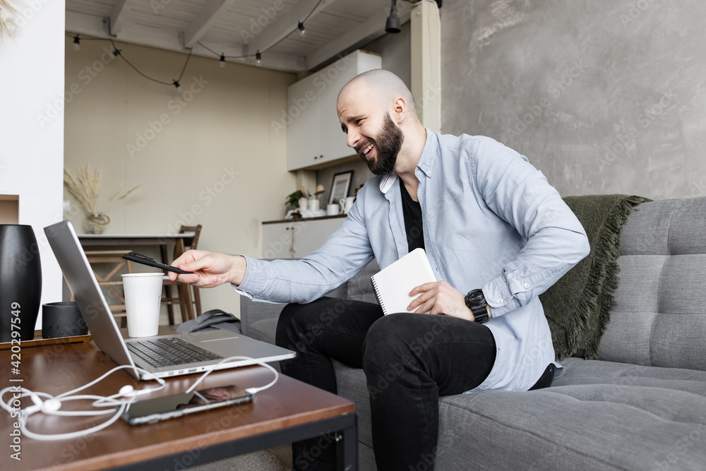 A young guy in a blue shirt and black jeans is studying online from home using a computer and a diary for writing in a good mood. Concept of work and study online A young guy in a blue shirt and black jeans is studying online from home using a computer and a diary for writing in a good mood. Concept of work and study online