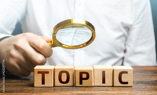 Man examines blocks with topic with a magnifying glass. Conduct research, get an topic explanation. Become an expert, understand the case. Understanding the subject. Assessing value of information photo