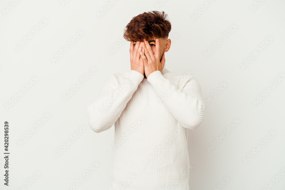 Young Moroccan man isolated on white background blink at the camera through fingers, embarrassed covering face. Young Moroccan man isolated on white background blink at the camera through fingers, embarrassed covering face.