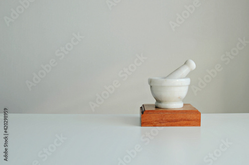 Mortar and pestle made of white stone on a wooden stand. Stylish interior mockup, copy space.