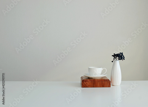 A white cup and saucer and a vase. Stylish interior mockup  copy space.