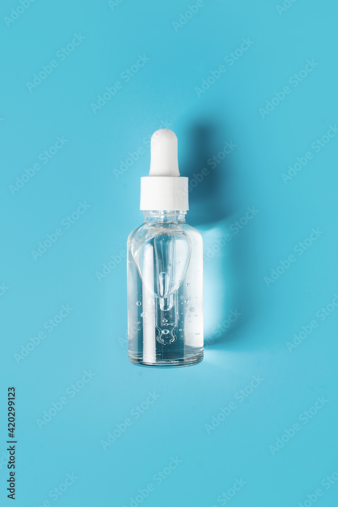 Beauty concept with bottle of serum on blue background Beauty concept with bottle of serum on blue background