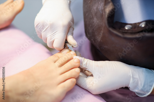 pedicure master holds nail clippers in his hands and cuts off the toenails