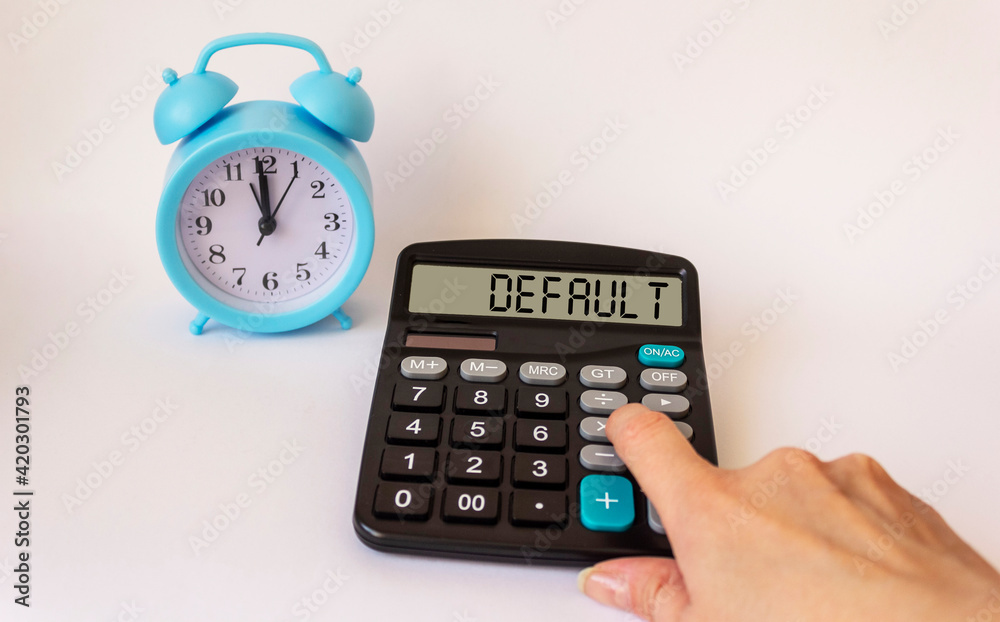 DEFAULT calculator on display isolated on white background, near an alarm clock and a female hand DEFAULT calculator on display isolated on white background, near an alarm clock and a female hand