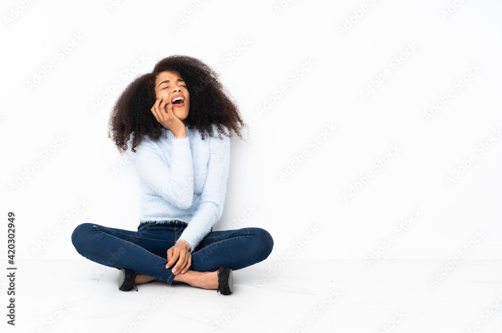 Young african american woman sitting on the floor with toothache Young african american woman sitting on the floor with toothache