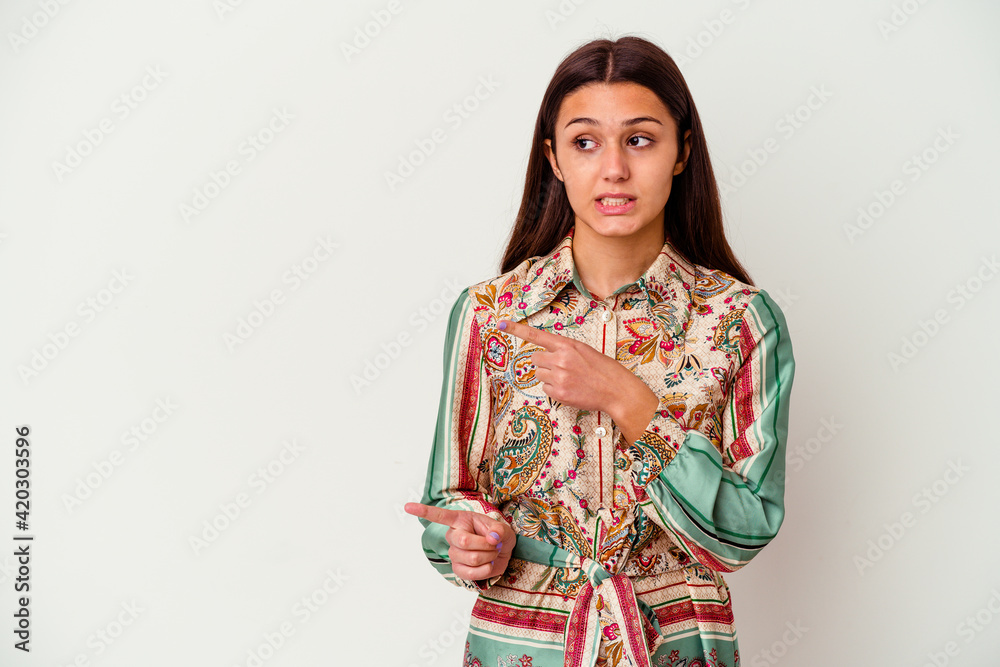 Young Indian woman isolated on white background shocked pointing with index fingers to a copy space. Young Indian woman isolated on white background shocked pointing with index fingers to a copy space.