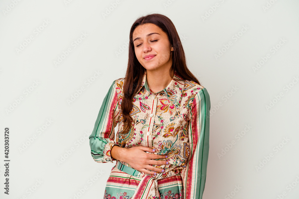 Young Indian woman isolated on white background touches tummy, smiles gently, eating and satisfaction concept. Young Indian woman isolated on white background touches tummy, smiles gently, eating and satisfaction concept.