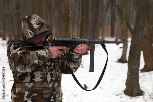 The man with machine gun in the snowy forest