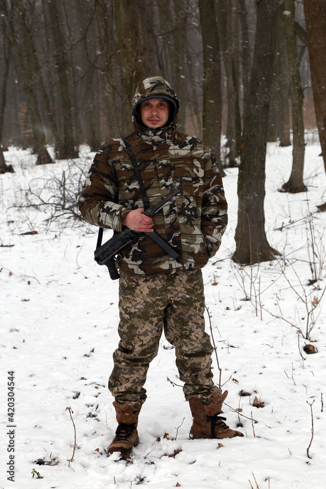 The man with machine gun in the snowy forest