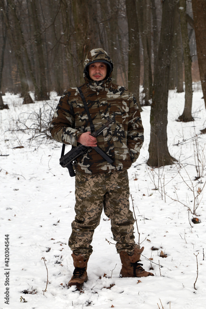 Fototapeta premium The man with machine gun in the snowy forest