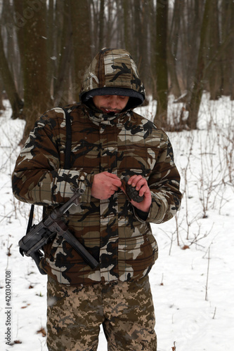 A soldier with hand grenade in the snowy forest
