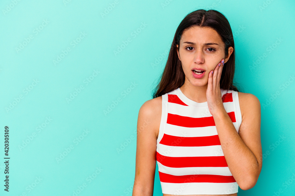 Young Indian woman isolated on blue background shouts loud, keeps eyes opened and hands tense. Young Indian woman isolated on blue background shouts loud, keeps eyes opened and hands tense.