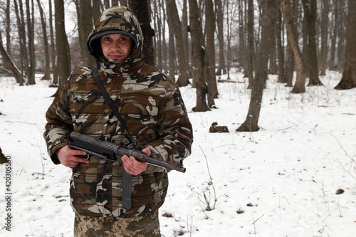 The man with machine gun in the snowy forest