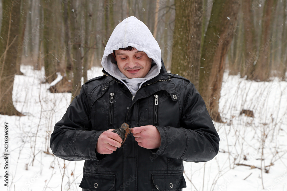 A man with grenade in his hands in the snowy forest
