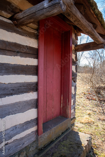 vertical view of colonial log cabin red door