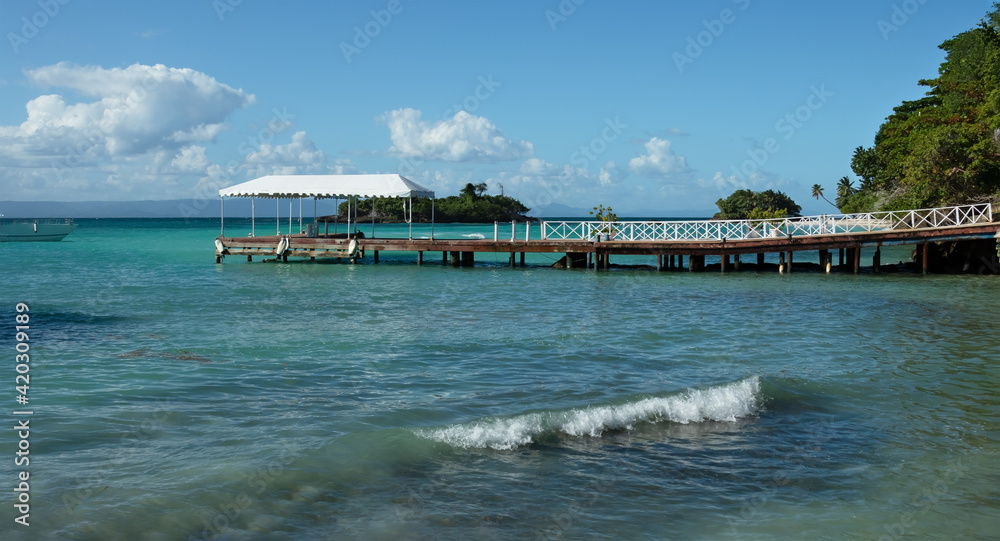 seascape with wooden pier and green island on the horizon