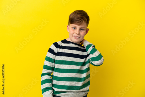 Little redhead boy isolated on yellow background laughing