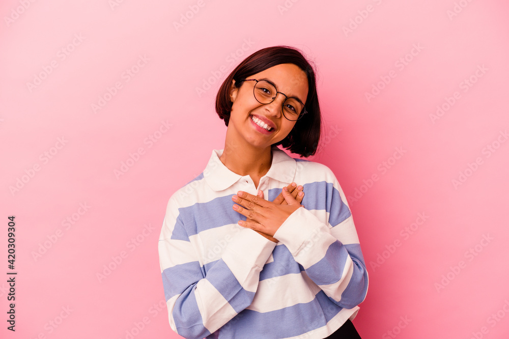 Young mixed race woman isolated on pink background has friendly expression, pressing palm to chest. Love concept. Young mixed race woman isolated on pink background has friendly expression, pressing palm to chest. Love concept.