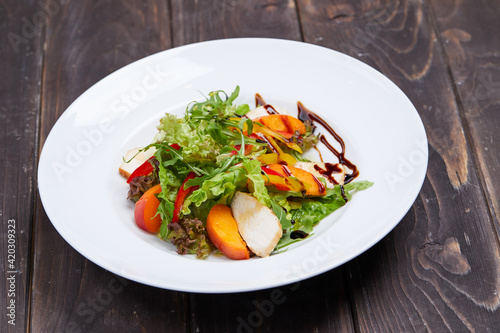salad with grilled peach on wooden background