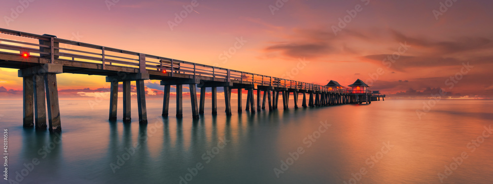 Panoramic shot of a scenic colorful sunset at the beach with breathtaking boardwalk