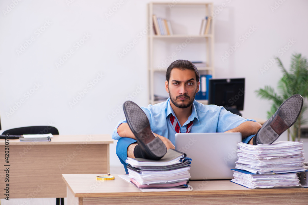 Young male employee unhappy with excessive work in the office Young male employee unhappy with excessive work in the office