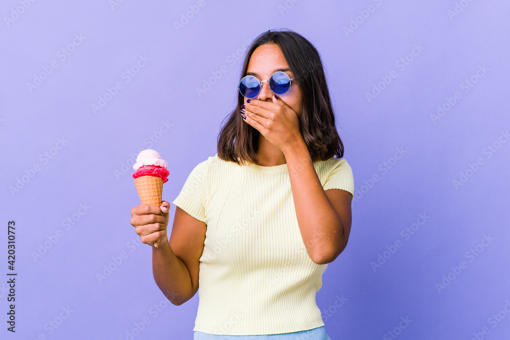 Young mixed race woman eating an ice cream thoughtful looking to a copy space covering mouth with hand. Young mixed race woman eating an ice cream thoughtful looking to a copy space covering mouth with hand.