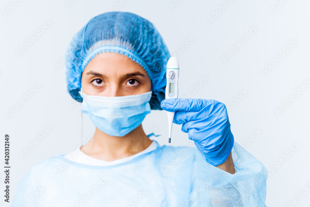 Young mixed race surgeon woman holding a thermometer isolated Young mixed race surgeon woman holding a thermometer isolated