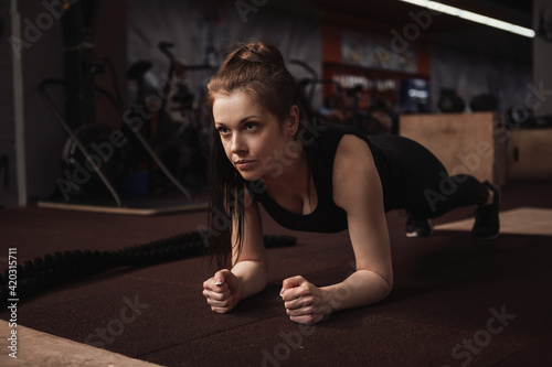 Beautiful sportswoman doing plank exercise at the gym