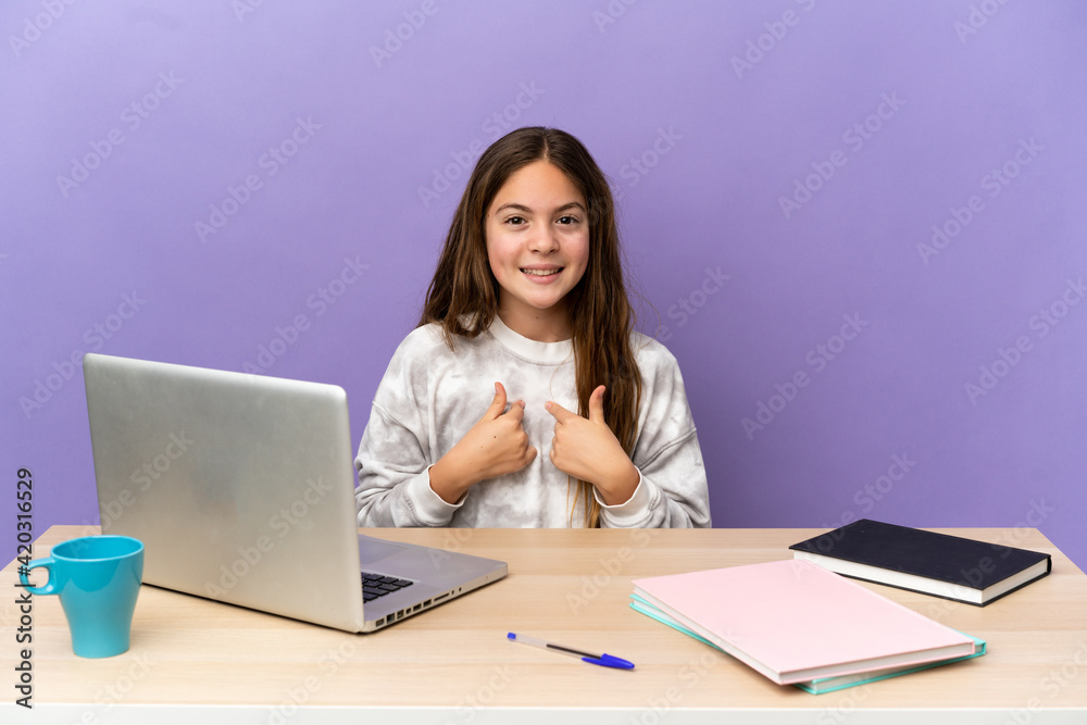 Little student girl in a workplace with a laptop isolated on purple background with surprise facial expression