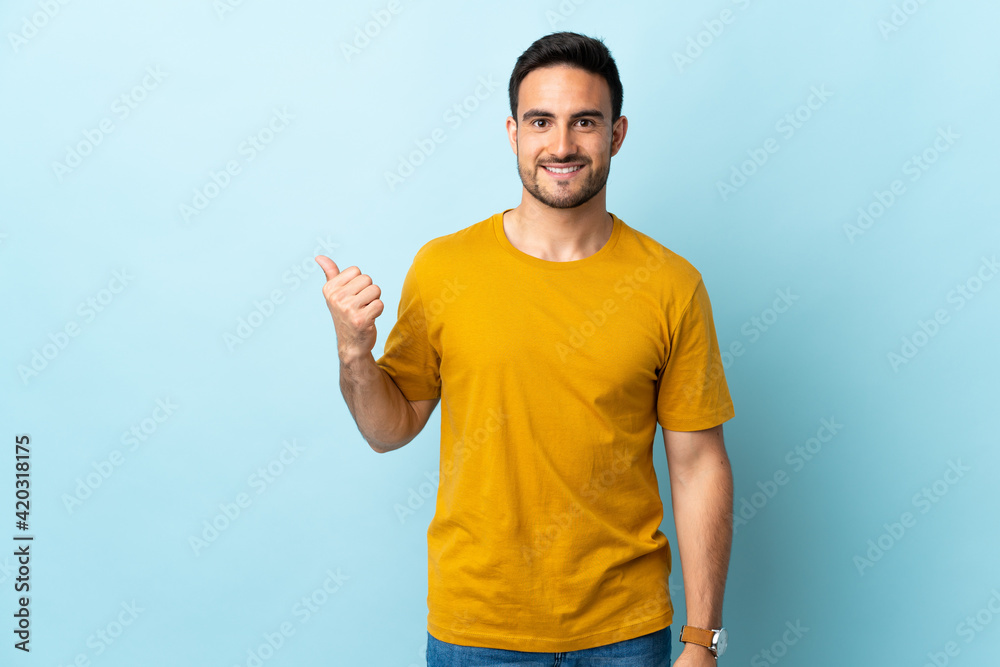 Young handsome man over isolated background pointing to the side to present a product Young handsome man over isolated background pointing to the side to present a product