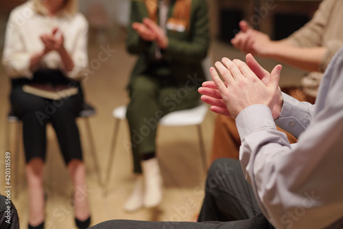 Patients of mental support group clapping hands while sitting in circle during psychological session