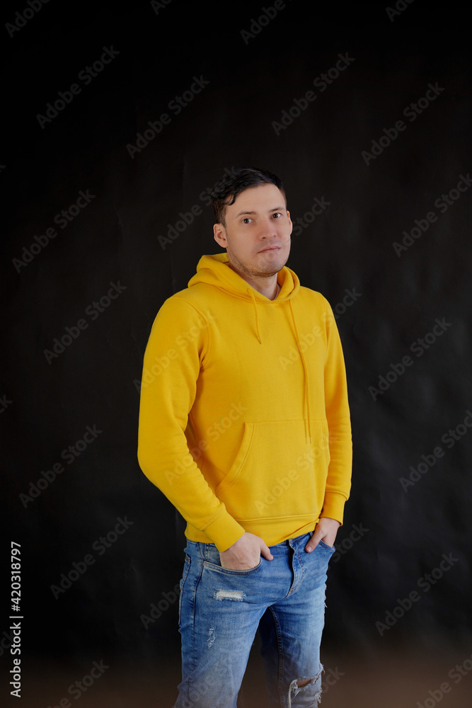Portrait of young man on black background. Handsome guy in yellow hoodie posing on dark background. Portrait of young man on black background. Handsome guy in yellow hoodie posing on dark background.