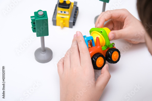 A boy playing toy cars on a white table