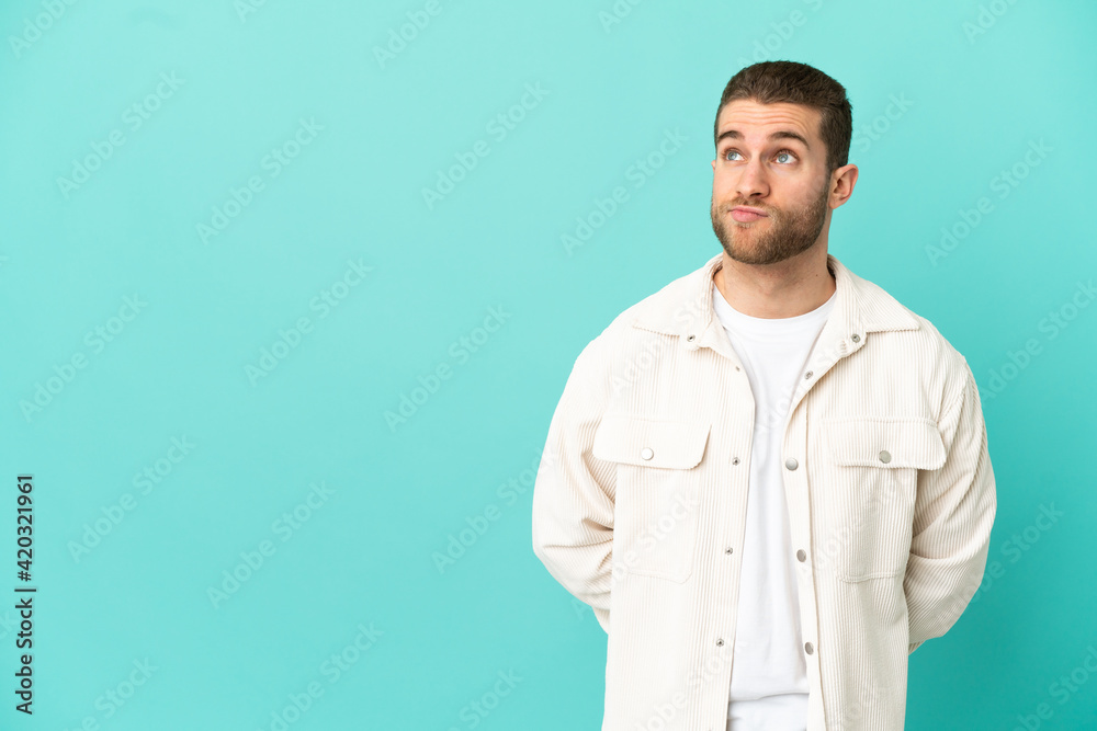 Handsome blonde man over isolated blue background and looking up Handsome blonde man over isolated blue background and looking up